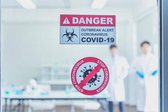 Biohazard disease alert corona outbreak sign on glass wall laboratory science center. Medical care clinic with hazard alert sign. Medical Healthcare concept. - Powered by Adobe