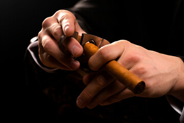 Close-up photo of a male hands holding a guillotine and a cigar. - Powered by Adobe