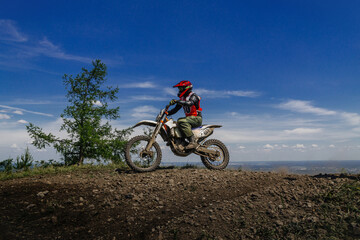 Fototapeta na wymiar enduro motorcycle rider on mountain in background blue sky