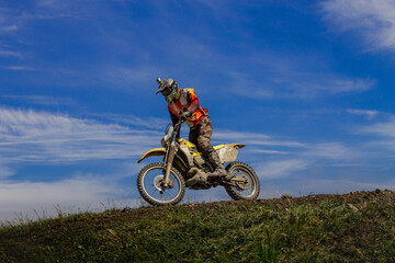 Fototapeta na wymiar enduro motorcycle racer on mountain in background blue sky