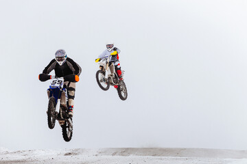 two motorcycle racers jump winter enduro race