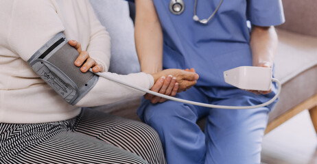 Homecare nursing service and elderly people cardiology healthcare. Close up of young hispanic female doctor nurse check mature caucasian man patient heartbeat using stethoscope during visit