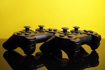 Wireless joystick gamepad controllers on a mirror surface on a yellow background © Michael
