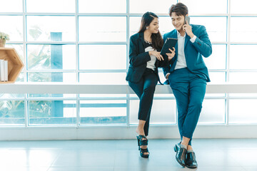 Happy business couple standing together  checking work on tablet near the window background. COPY SPACE.