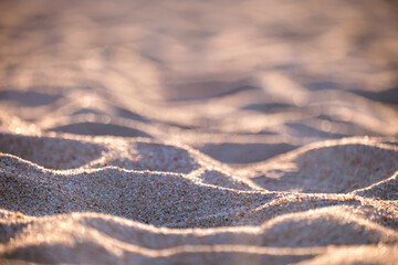 Close up of clean yellow sand surface covering seaside beach illuminated with evening light. Travel and vacations concept