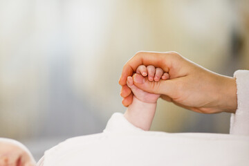 Close up mother holding tiny hand of little newborn baby boy girl, helping hands, bonding different...