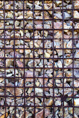 Front view of wire cage basket retaining wall filled with stones for noise barrier