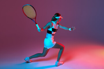 Back view of professional tennis player playing tennis over pink-purple background in neon light....