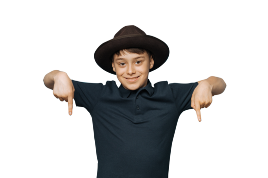 Young boy isolated transparent background in brown hat with a brim and dark blue t-shirt pointing down. Look there, please. Handsome European kid offers to go downstairs. Down below
