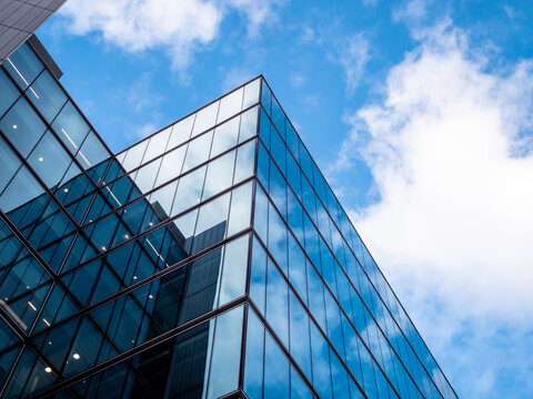 London UK - Close up of Business Financial district office headquarters within the modern skyscrapers. Blue clean modern glass wall with sky and cloud reflection. Capital city commercial district