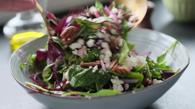 Salad making video 4k. Fresh nutrition salad of beetroot, babyspinat, onions, rukkola, pecan and white soft cheese. Homemade cooking footage.