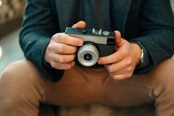 Faceless shot of male hands holding a vintage camera while sitting outdoors.