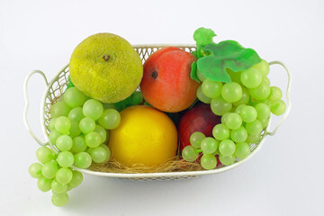 wire basket filled with various fruits on a white background