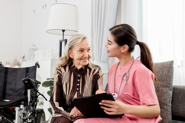 Pleasant confident skilled blond woman doctor in glasses and white coat, visiting patient, senior lady, at home for treatment control, handshaking and giving recommendations. Healthcare concept