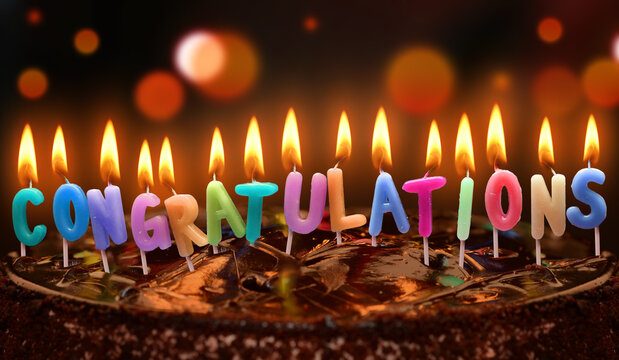 Colorful lit Congratulations candles on chocolate cake