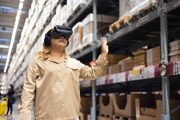 Fototapeta premium Plus size female worker inspecting box of products and use virtual reality technology for innovative VR while working in large warehouse