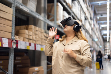Fototapeta premium Plus size female worker inspecting box of products and use virtual reality technology for innovative VR while working in large warehouse