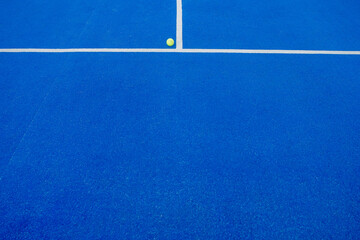 ball next to the line of a blue tennis paddle tennis court at sunset