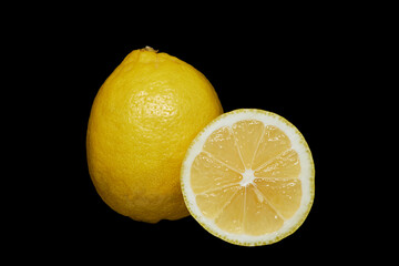 ripe lemon and a cut part of it on a black background