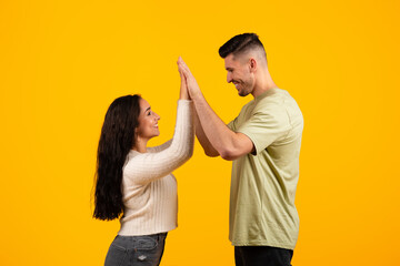 Cheerful young arabic woman and guy in casual, holding hands, doing high five, celebrating victory