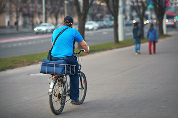 Delivering food on bicycle, courier cycling with pizza bag, deliver food to customers. Worker with thermal backpack delivering pizza from restaurant.
