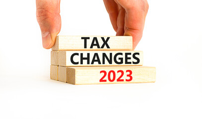 Tax changes 2023 symbol. Concept words Tax changes 2023 on wooden blocks on a beautiful white table white background. Businessman hand. Business Tax changes 2023 concept. Copy space.