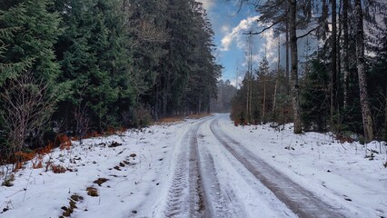 Obraz premium Snow is melting on a forest road. Ice and water on a snowy road. Spring came.