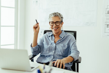Successful in the design industry, senior woman smiles at the camera in her office