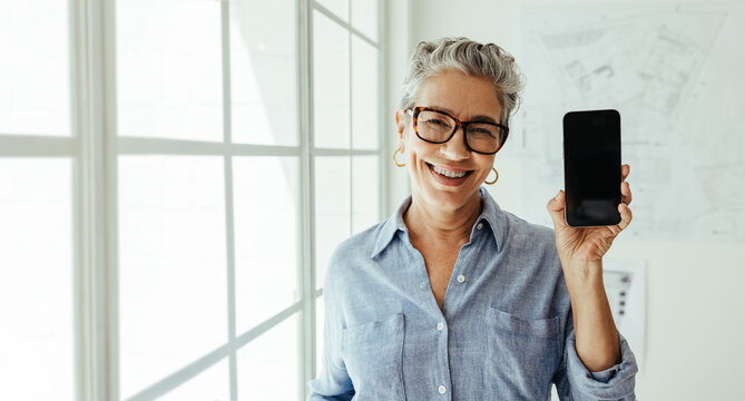Mobile apps for architects: Happy senior architect holding a mobile phone with a black screen