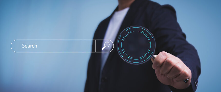 Businessman holding magnifying glasss earch for Browsing Internet Data Information Networking Concept, .Internet search page on computer screen.