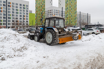 A tractor with a road cleaning brush is parked in the parking lot