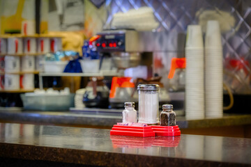 The charm of a local diner in Binghamton in Upstate NY. Retro feeling in this eating establishment.  Salt, Pepper, and Sugar on the counter wats to be used.