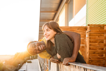 Joyful diverse couple hugging on balcony