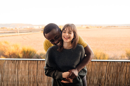 Joyful diverse couple hugging on balcony