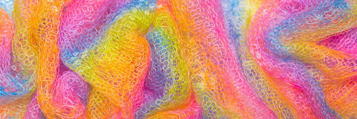 Knitted surface woolen items rainbow colored as a background. Closeup of soft multicolored knitted texture patterns. Warm winter clothes. Background textile surface with copy space for text. blurred