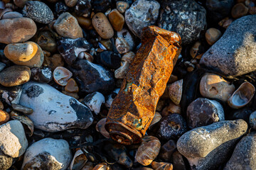 ALooking down at a rusty can washed up on a pebble beach