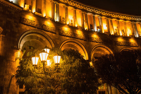Lamp post with multiple lanterns next to the government building in Yerevan, lit with warm colors.