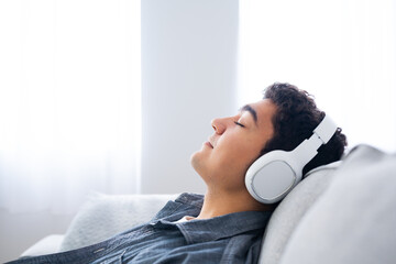 Hispanic teenager boy listening to relaxing music on headphones