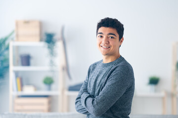 Portrait of handsome hispanic teenager boy with crossed arms looking and smiling to camera