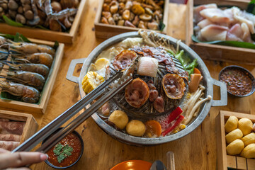 Closeup of grill with deliciouse seafood, shrimp, crab, mussle, pork sausage and vegetable on wood...