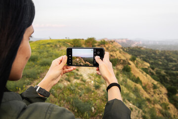 Europe - 15th may, 2022: caucasian woman hold smartphone take photo of beautiful nature outdoors on...