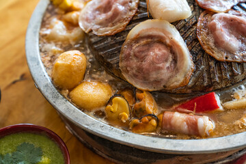 Closeup of grill with deliciouse seafood, shrimp, crab, mussle, pork sausage and vegetable on wood...