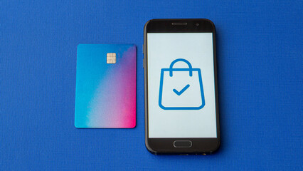Mobile phone next to credit or debit card. Online shopping using smart phone and card. Purchase complete symbol on screen.