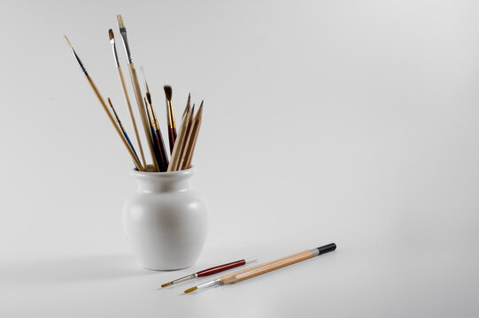watercolor artists brushes and sketching pencils in a vase isolated on a white background