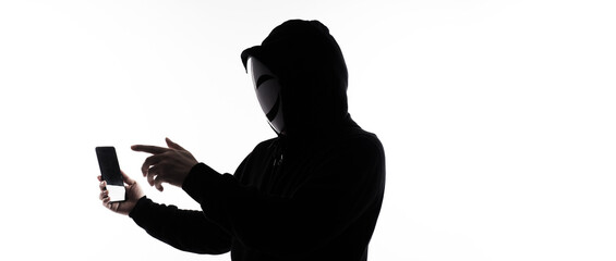 Hacker Anonymous and face mask with smartphone in hand. Man in black hood shirt holding and using mobile phone on white background. Represent cyber crime data hacking or stealing personal data concept