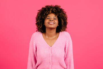 Fototapeta premium Satisfied young black curly lady with braces and closed eyes inhales deeply, enjoys freedom, raises her head
