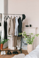 Clothes on hangers near minimalistic decorative fire place in stylish apartment.