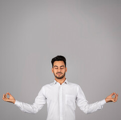 Zen Concept. Calm Arab Businessman Meditating Over Grey Background