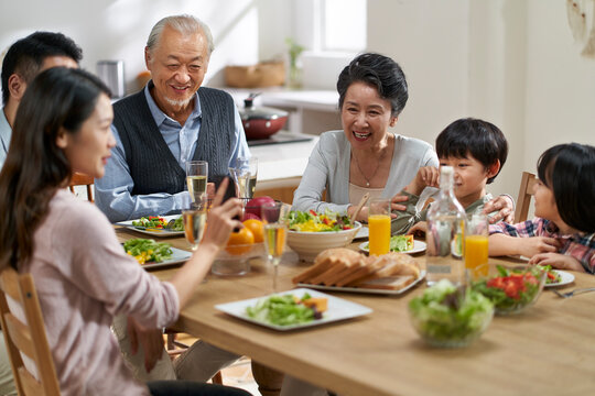 multi generational happy asian family eating meal at home