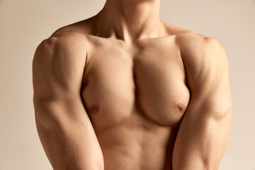 Fototapeta premium Relief body shape. Cropped image of strong, relief, muscular male breast and hands over grey studio background. Masculinity. Concept of men's health and beauty, body and skin care, fitness. Body art